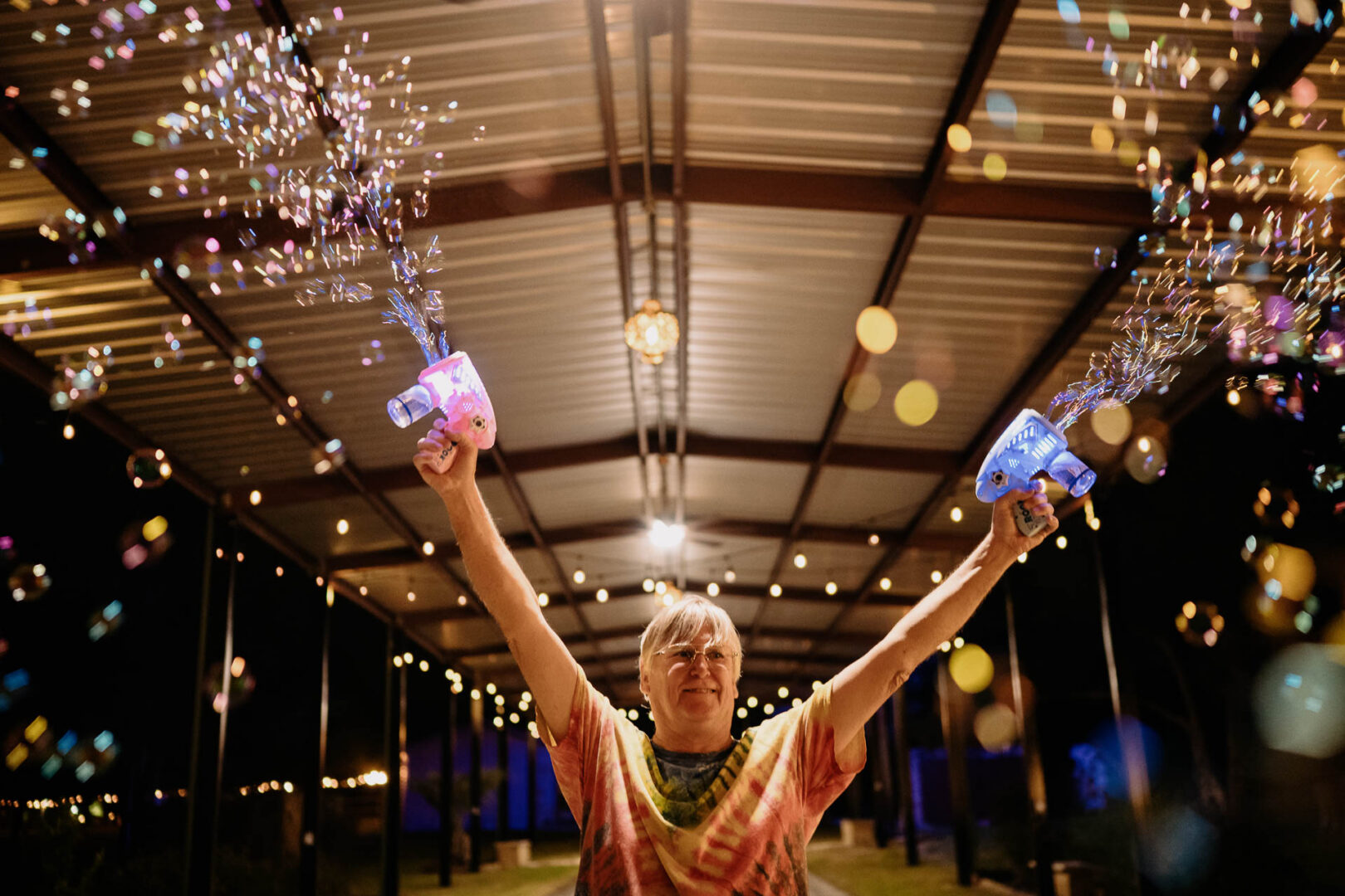 Vibrant Spring Wedding at Shiraz Gardens in Bastrop 87 Joyful documentary wedding photo of the bride celebrating during the reception beneath string lights at Shiraz Gardens in Bastrop, Texas.