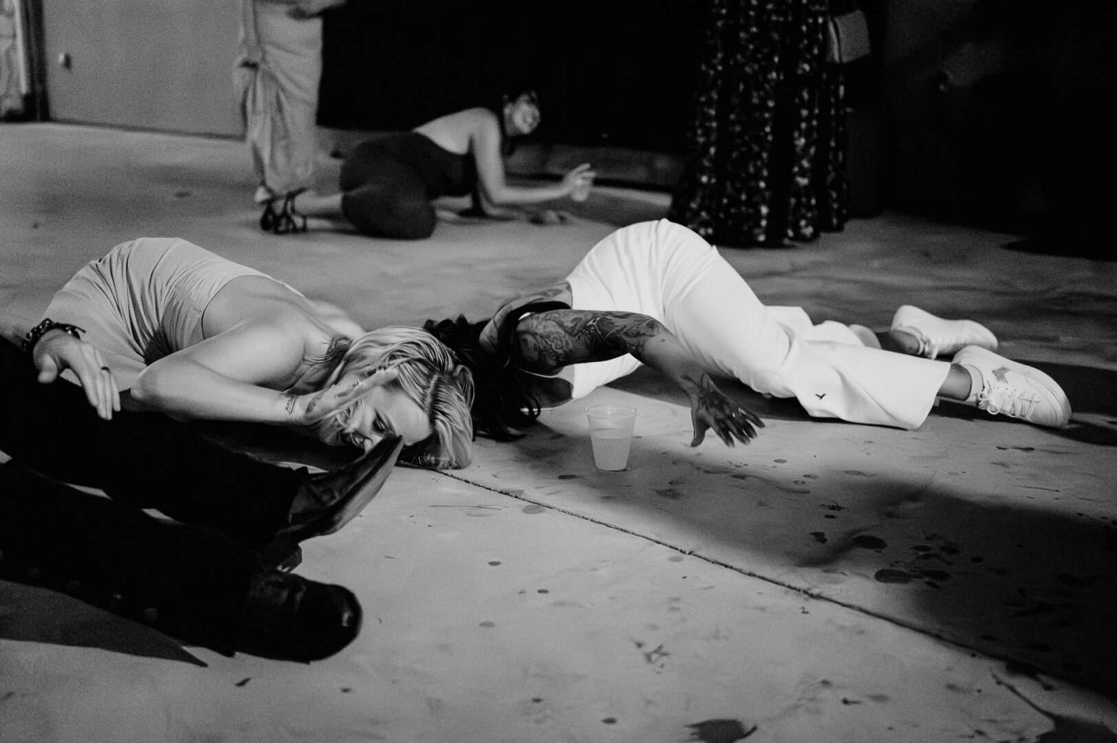 Vibrant Spring Wedding at Shiraz Gardens in Bastrop 88 Black and white candid wedding reception photo of guests lying on the dance floor during the celebration at Shiraz Gardens in Bastrop, Texas.
