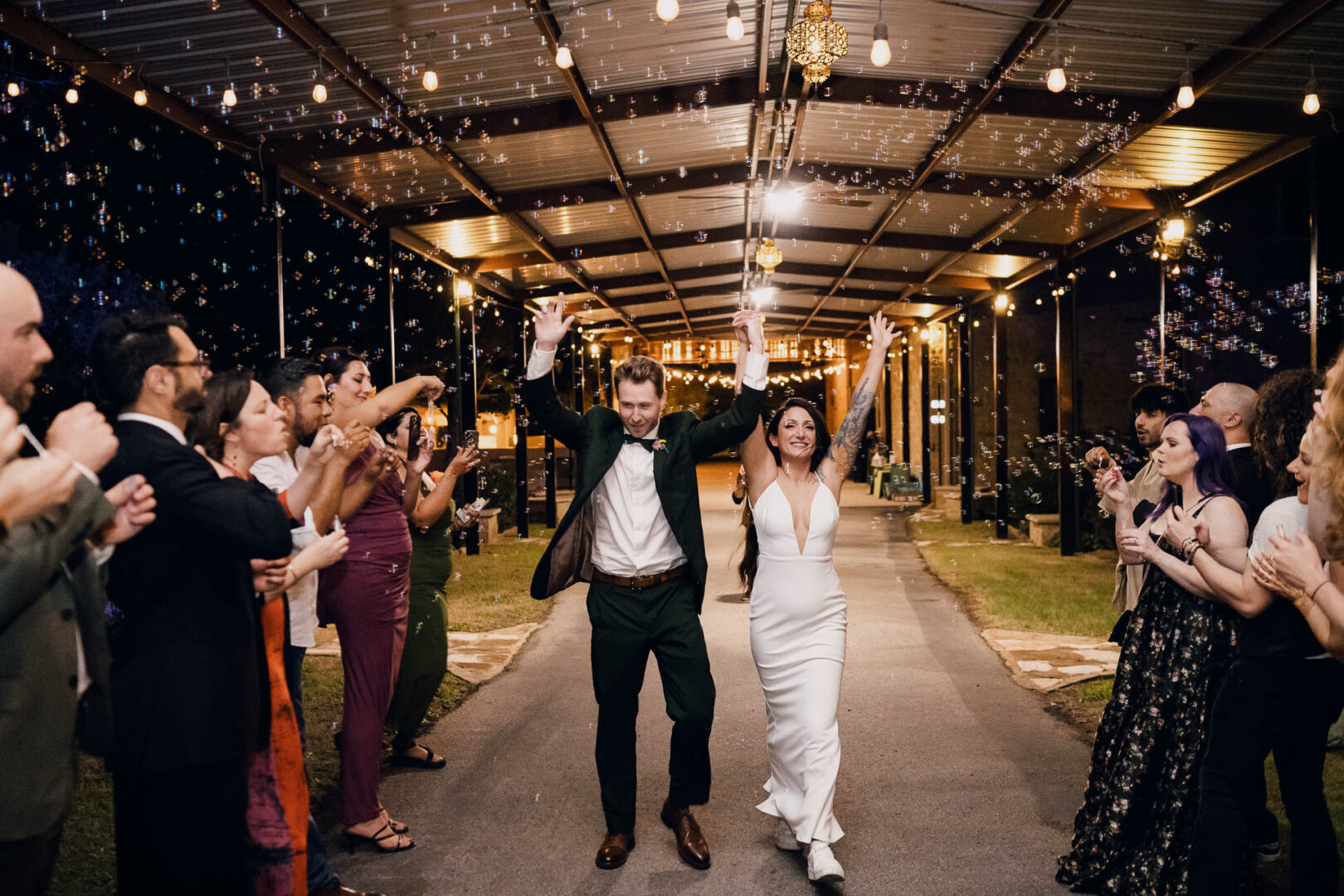 Vibrant Spring Wedding at Shiraz Gardens in Bastrop 91 Documentary wedding photo of the bride and groom walking through guests during their sparkler exit at Shiraz Gardens in Bastrop, Texas.