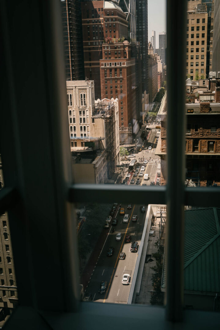 Manhattan buildings framed by hotel window curtains before the wedding day begins.