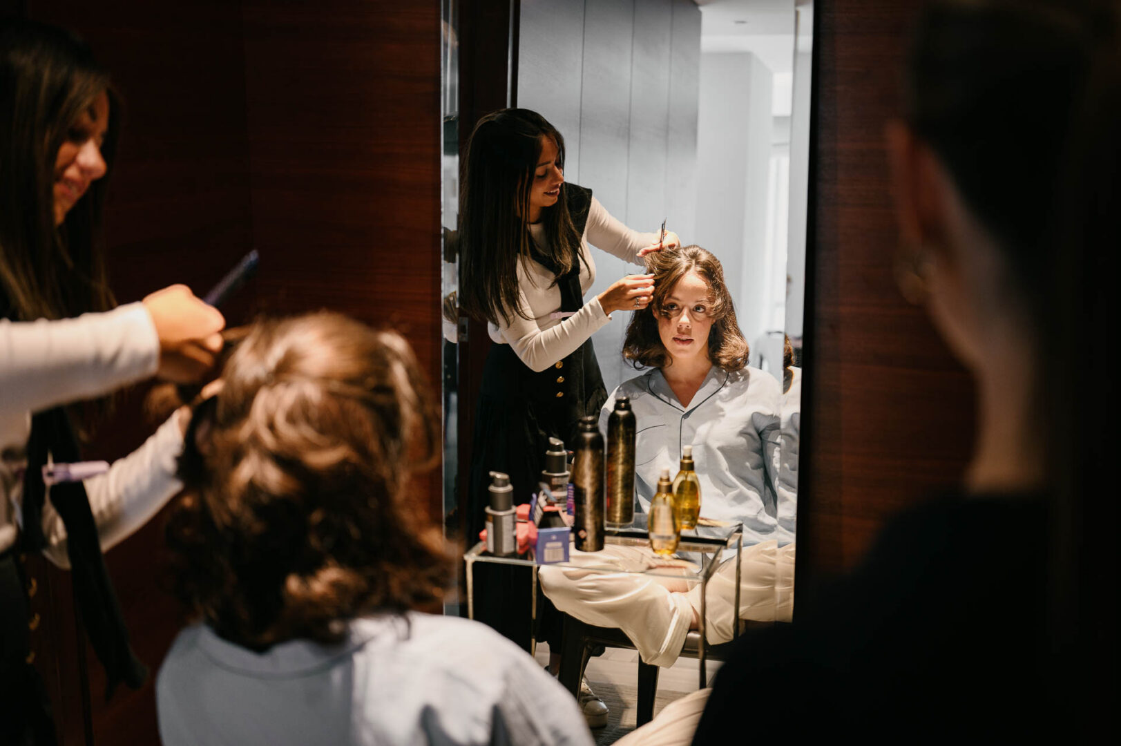 Bride being helped during wedding preparations in the bride’s hotel suite.