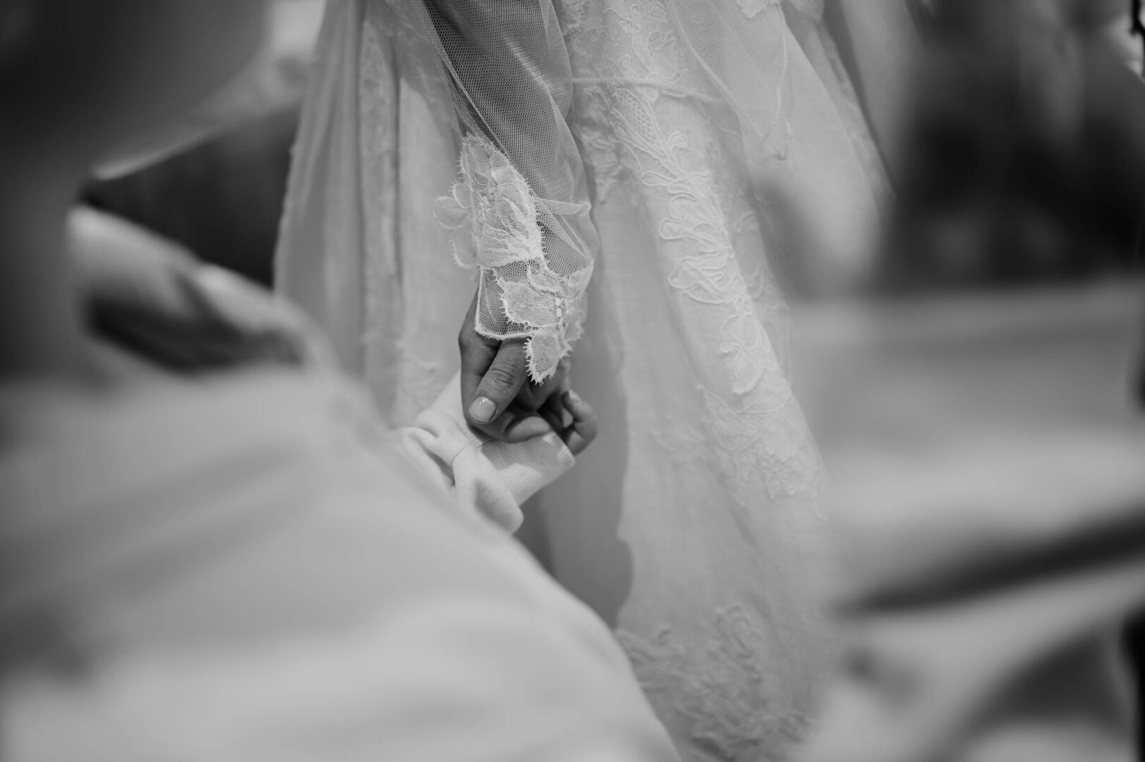 Close-up of hands and wedding dress detail during bridal preparations.