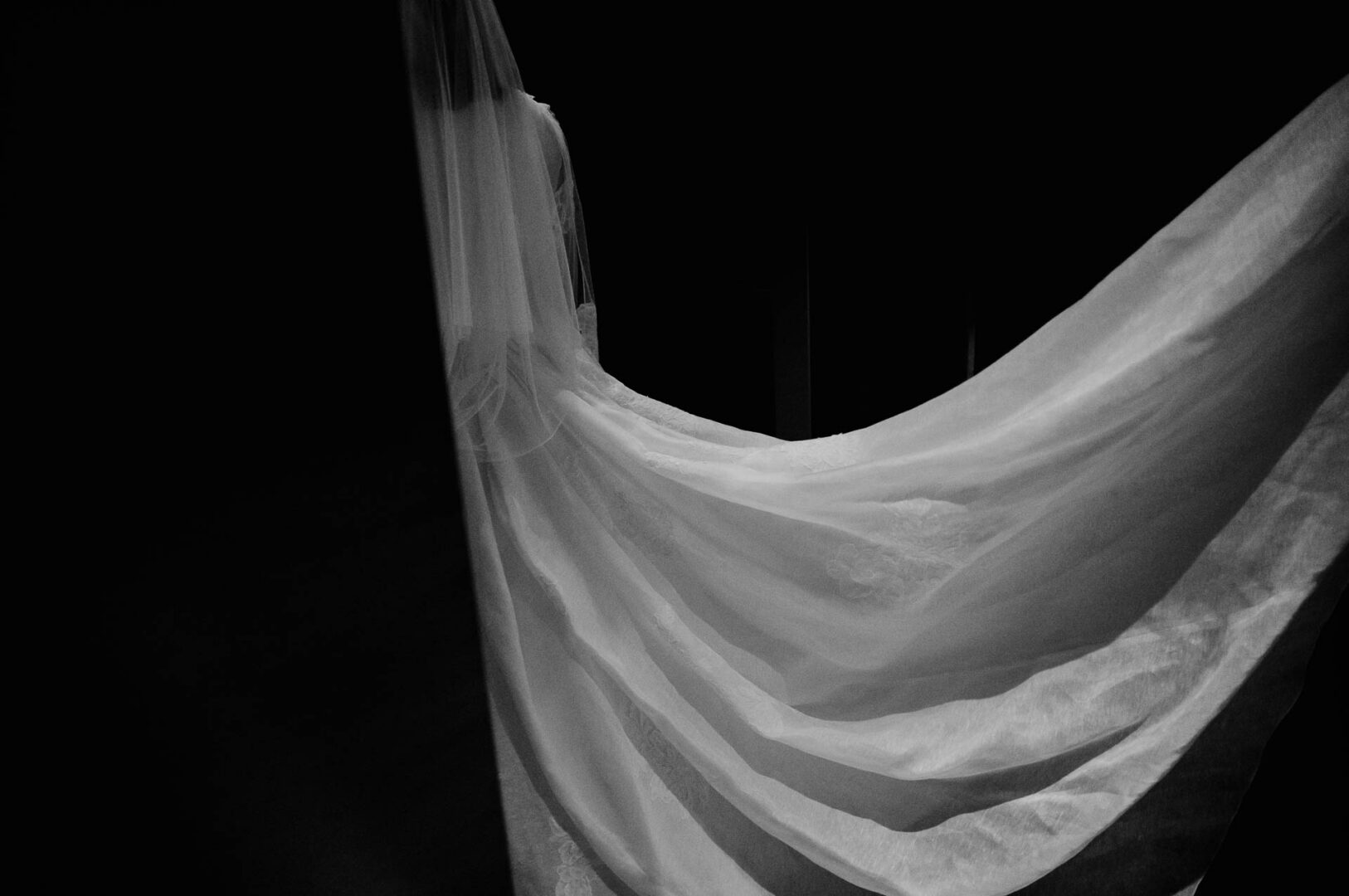 Black and white silhouette of a bride’s veil before the ceremony.