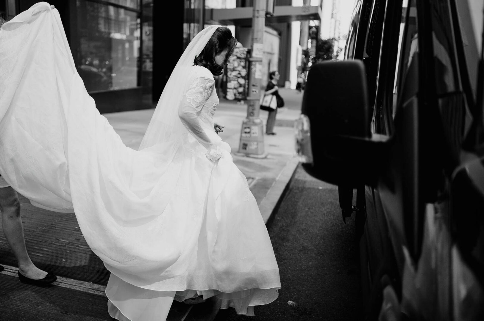 Bride walking along a Manhattan sidewalk in her wedding dress.