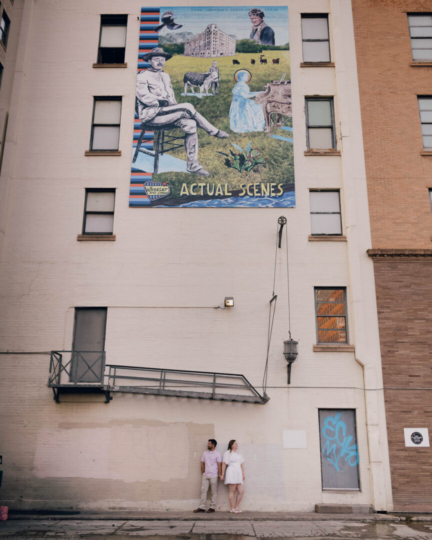 Couple admiring mural on building.