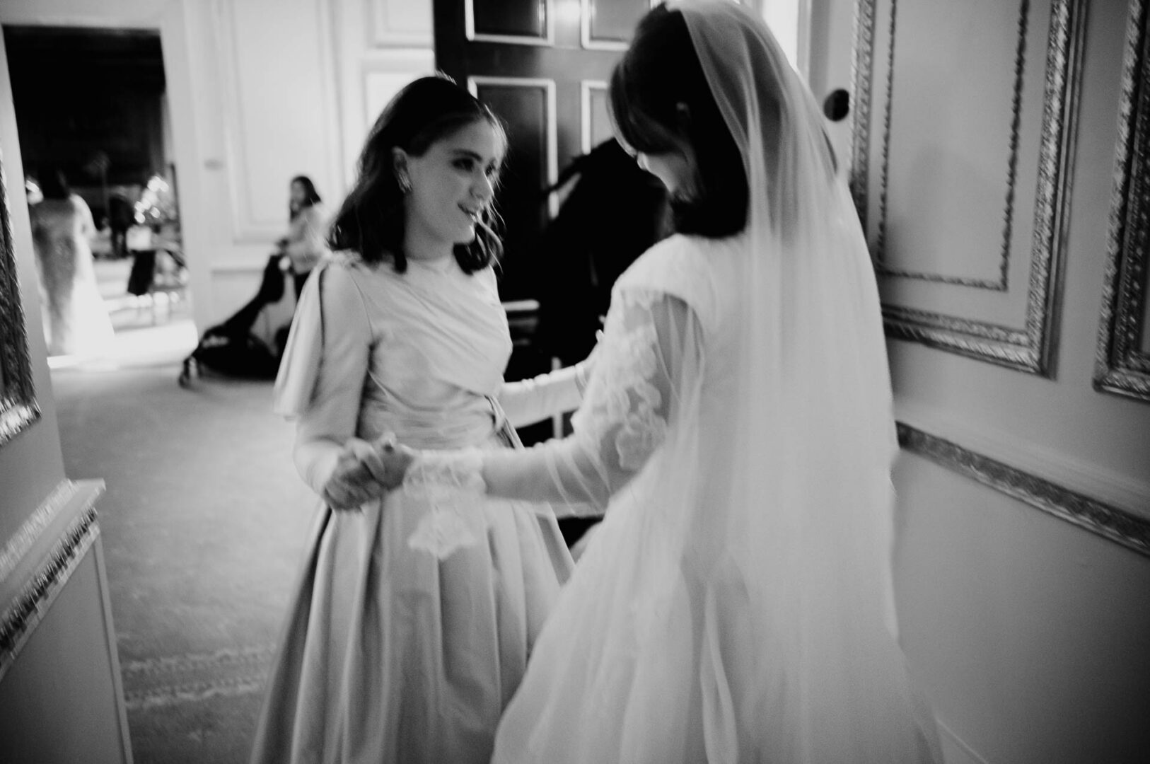 Black and white photograph of an attendant adjusting the bride’s veil.