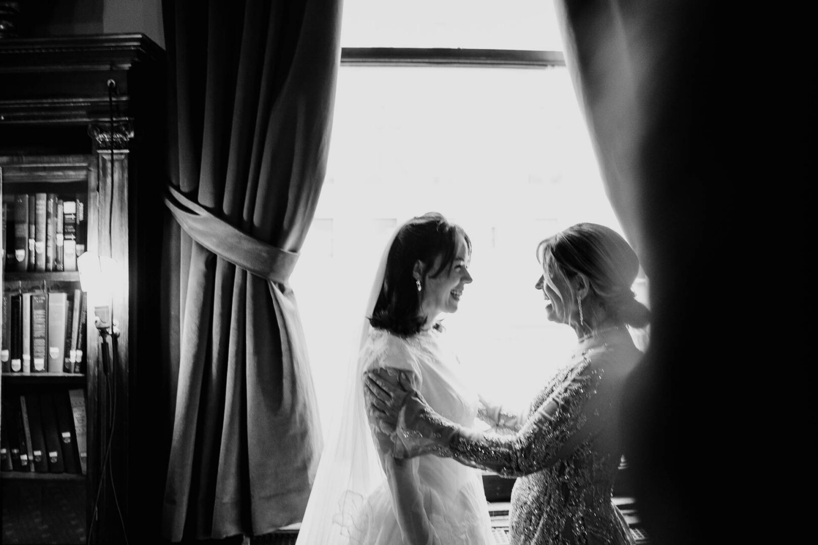 Bride with her mother in soft window light before the Orthodox Jewish ceremony.