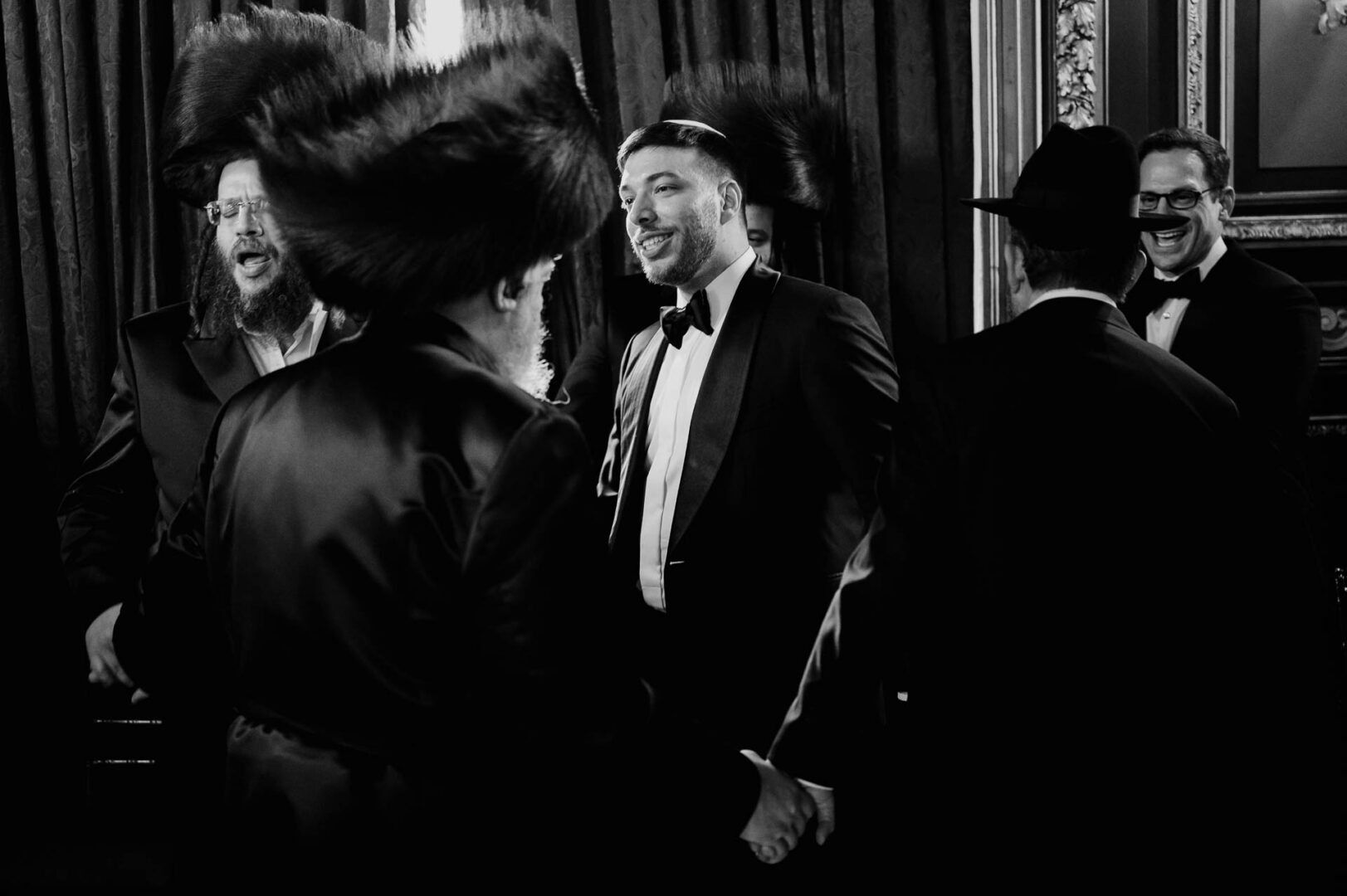 Black and white photograph of the groom smiling during a wedding tradition.
