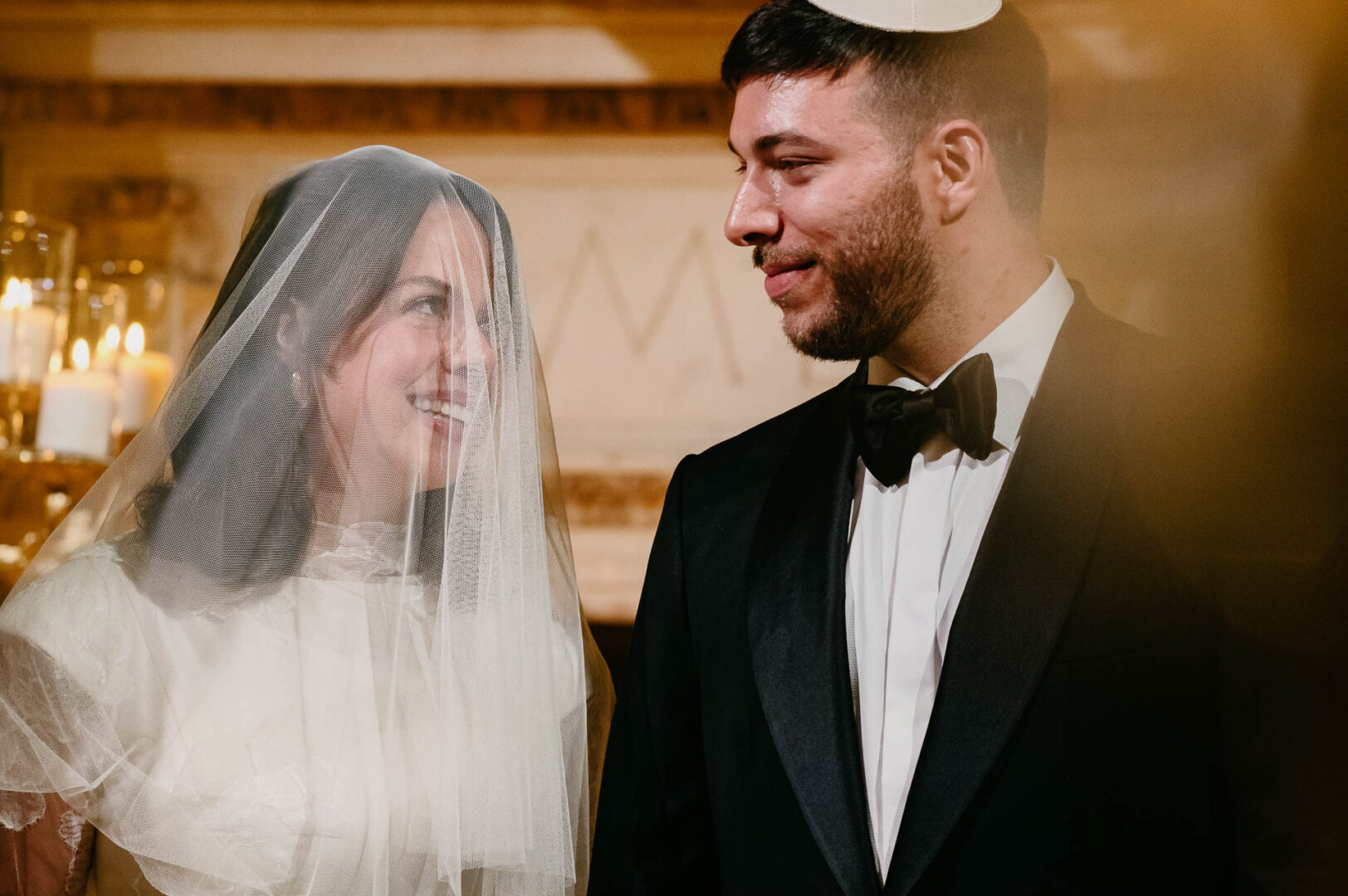Bride smiling behind her veil beside the groom during the ceremony.