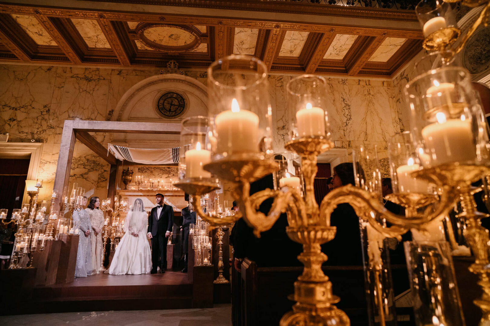Wide view of the ceremony room with guests seated beneath chandeliers.
