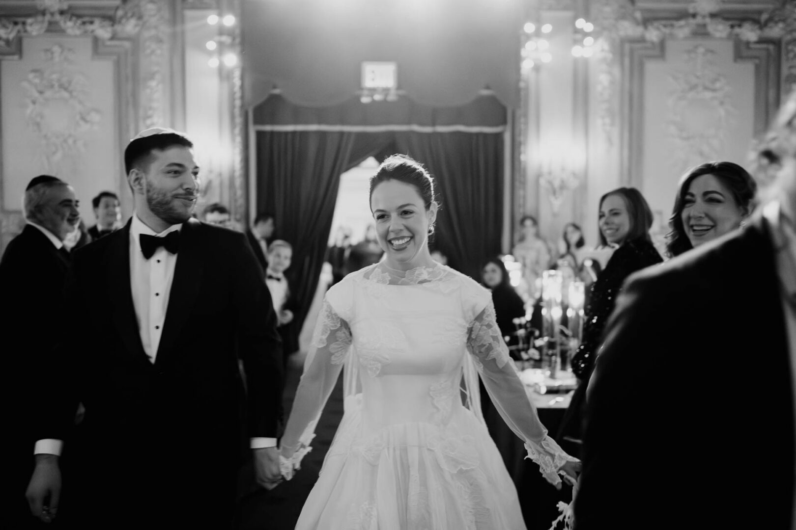 Couple joyfully entering wedding reception.