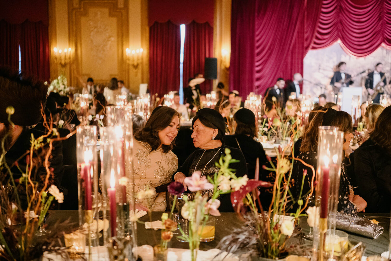 Two women conversing at elegant reception.