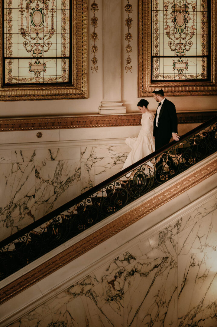 Couple descending elegant marble staircase.
