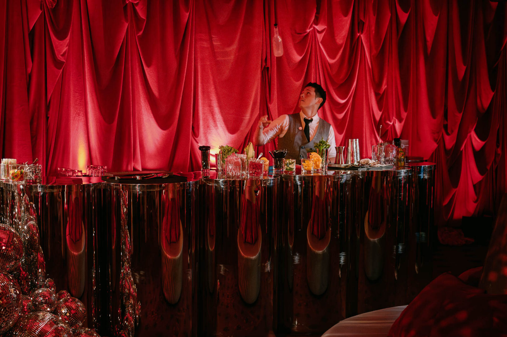 Bartender at a stylish red backdrop.