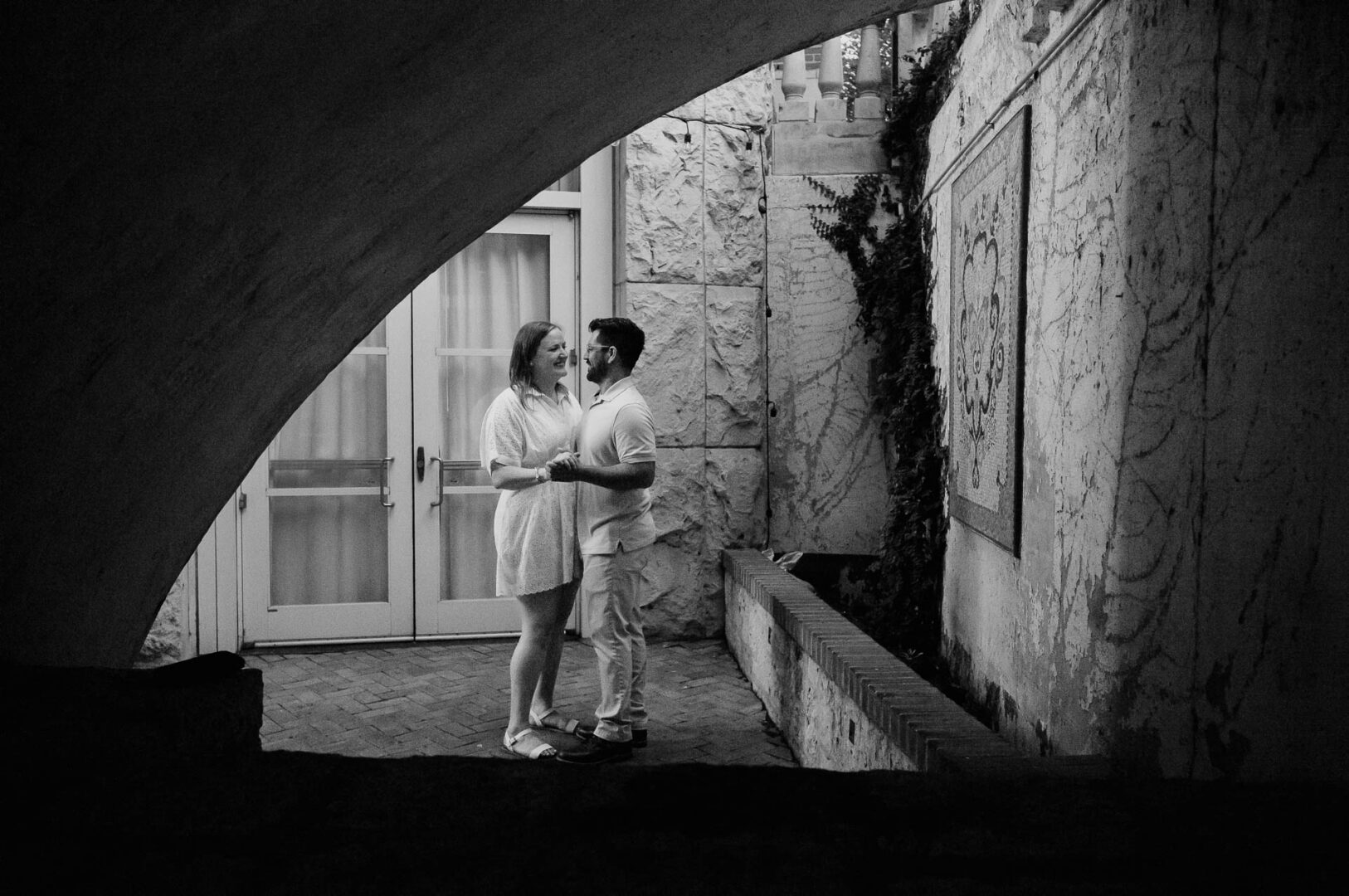 Couple embracing under an archway.
