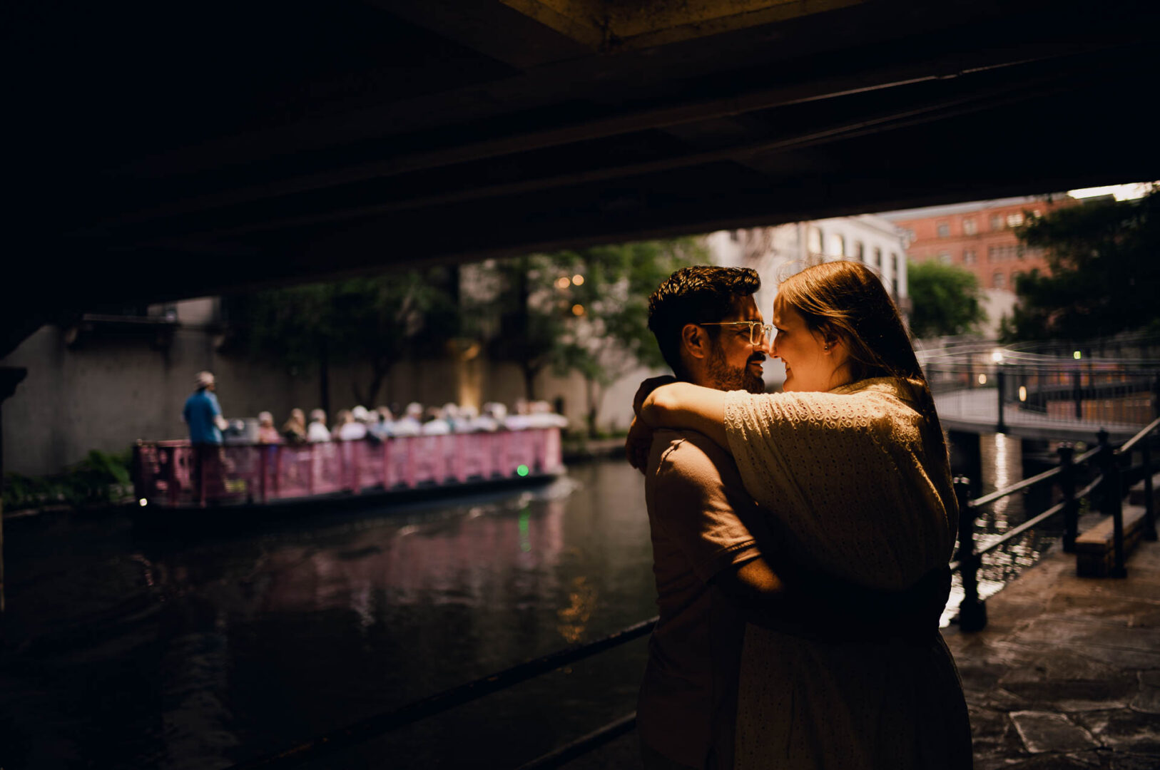 Couple embracing near a riverboat.