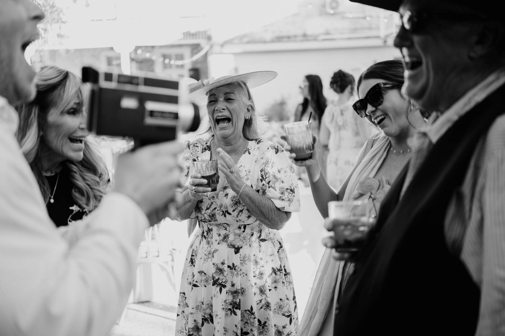 Black-and-white candid of guests laughing during the reception.