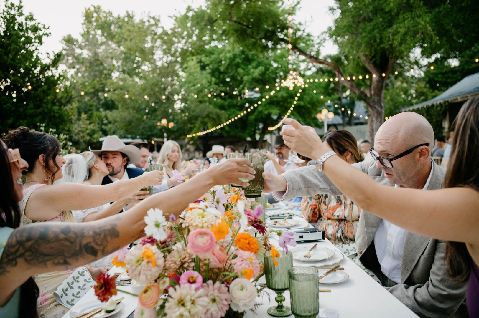 Guests celebrating with raised glasses during the outdoor reception.
