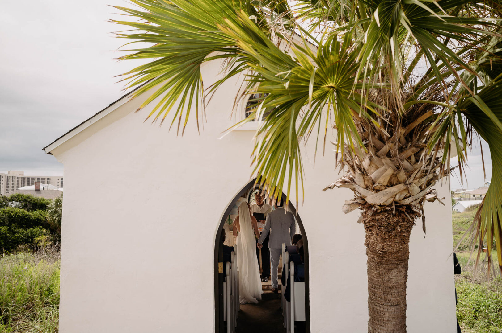 Chapel on the Dunes Wedding | Port Aransas, Texas | Mady+Roland 31 Palm fronds against the white exterior wall of the chapel.