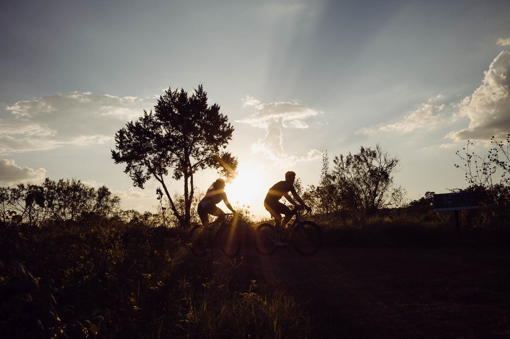 Silhouetted cyclists against sunset backdrop