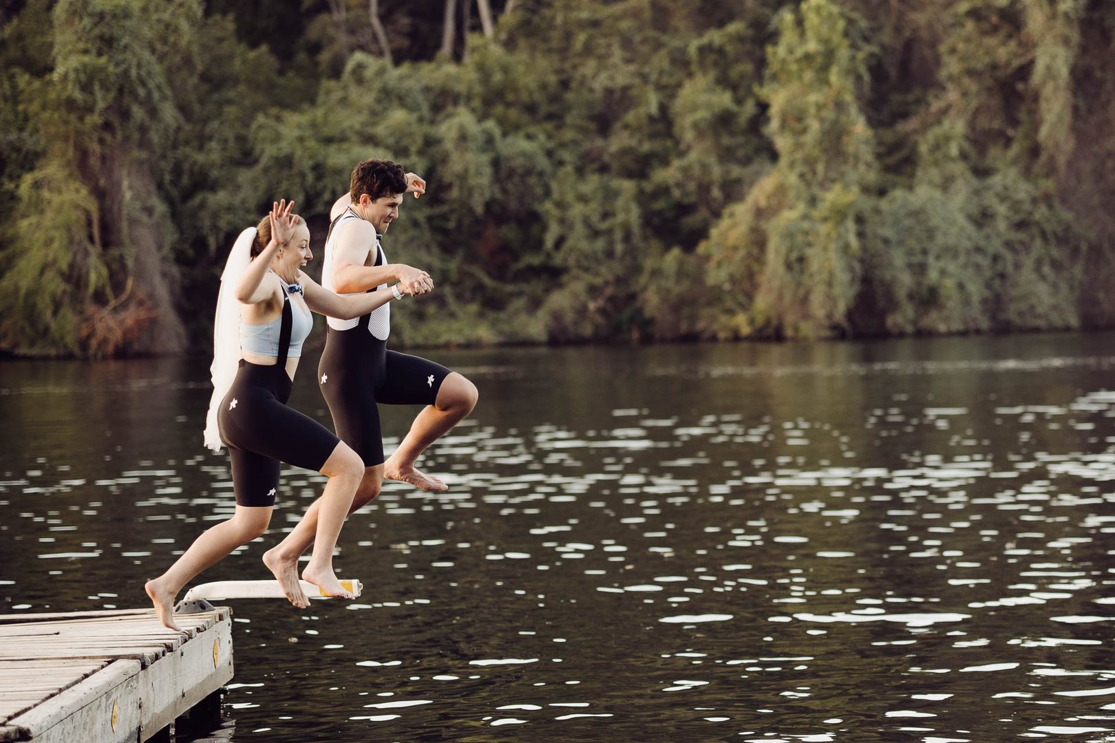 Couple jumping into a lake.