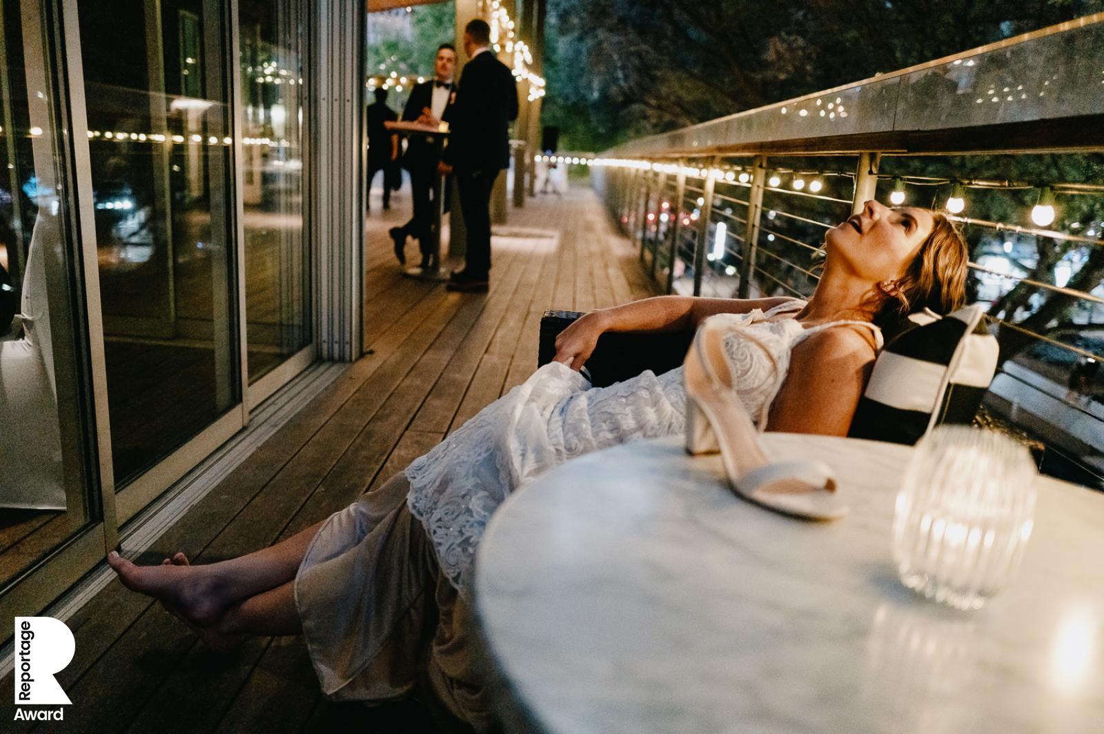 This Is Reportage - Award winning photo by Philip Thomas This Is Reportage - Award winning photo by Philip Thomas shows bride with her shoes off taking 5 minutes away from the hectic reception in Houston, Texas.
